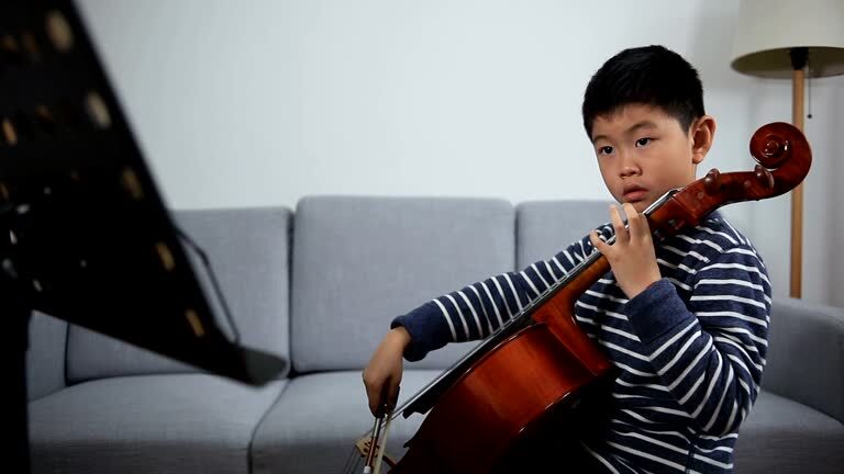 Asian boy studying cello indoors